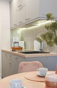 eine Küche mit weißen Schränken und einem Tisch mit Tassen in der Unterkunft Apartamenty na Wyspie - Villa Park - Parking in Świnoujście
