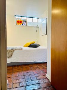 a bedroom with a bed with a yellow pillow on it at Casa Korallen in Varberg