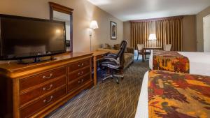 ein Hotelzimmer mit einem TV, einem Bett und einem Schreibtisch in der Unterkunft Best Western La Posada Motel in Fillmore