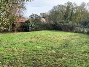 a field of grass with a fence in the background at Le petit cottage in Thollet +2 photos