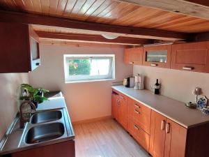 een keuken met houten kasten, een wastafel en een raam bij Holiday home right on the lake, Florczaki in Florczaki