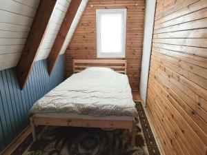een kleine kamer met een bed in een hut bij Holiday home right on the lake, Florczaki in Florczaki