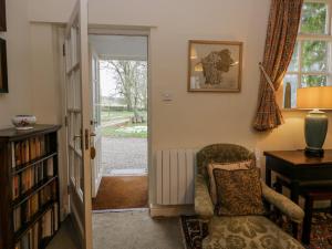 a living room with a chair and a radiator at Longlands Groom's Quarters in Cartmel