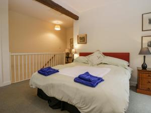 ein Schlafzimmer mit einem Bett mit blauen Handtüchern darauf in der Unterkunft Longlands Groom's Quarters in Cartmel