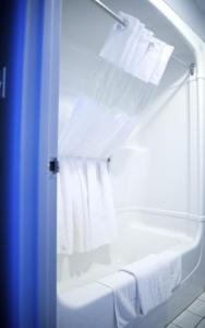 a white towel hanging from the side of a white shower curtain at St Christopher's Hotel in Channel-Port aux Basques