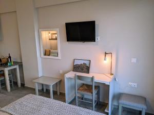 Habitación con escritorio y TV en la pared. en Evalia Apartments, en Hersonissos