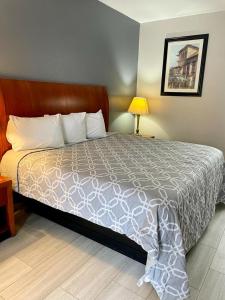 Una cama en una habitación de hotel con un colchón reforzado en American Way Inn & Suites en Memphis