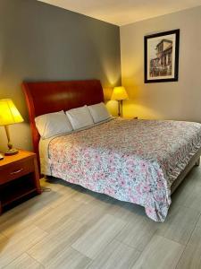 孟菲斯的住宿－American Way Inn & Suites，一间卧室配有一张床、两盏灯和两张桌子