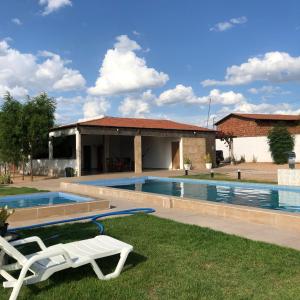a swimming pool with a chair and a house at Casa privado com 3 quartos e piscina in Logradouro