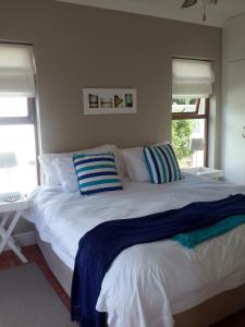 a bedroom with a large white bed with blue and white pillows at Island Nest in Knysna