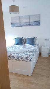 a white bed with blue pillows in a room at Apartamento Area Maior in Malpica +1 photo