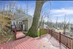 uma casa com uma árvore num deque de madeira em Cheerful home with amazing lake view em New Fairfield