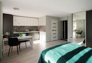 Cet appartement comprend une chambre avec un lit et une table ainsi qu'une cuisine. dans l'établissement Green bed by the pine forest, à Anykščiai