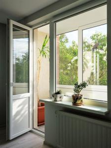 une chambre avec deux fenêtres et des plantes en pot sur un rebord de fenêtre dans l'établissement Green bed by the pine forest, à Anykščiai