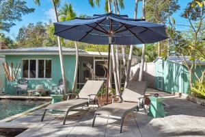 a patio with chairs and an umbrella next to a pool at Art Deco Pool house mile and a half to beach Pets Welcome in Lake Worth