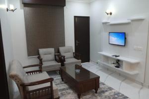 a living room with chairs and a table and a tv at Al Rasheed Apartments second floor apartment in Karachi