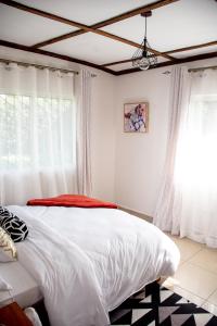 una camera da letto con un letto con lenzuola bianche e una finestra di The Nest Airbnb - Milimani, Kitale a Kitale