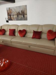 eine weiße Couch mit roten Kissen drauf in der Unterkunft La cabana lu' Vasile in Fundu Moldovei