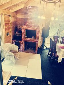 a living room with a brick fireplace and a television at La cabana lu' Vasile in Fundu Moldovei