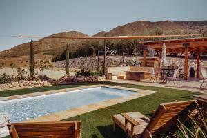 a swimming pool in a yard with a table and chairs at Finca el Mirador in Valle de Guadalupe