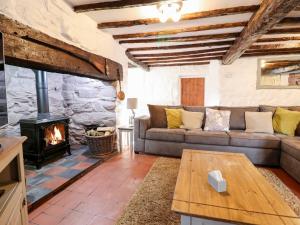 sala de estar con sofá y chimenea en Hen Argoed Cottage, en Llanbedr