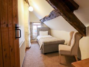 1 dormitorio con 1 cama y 1 silla en el ático en Hen Argoed Cottage, en Llanbedr