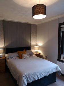 a bedroom with a large bed and a large light fixture at Y Cuddfan Gower in Swansea