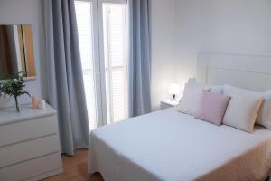 a white bedroom with a white bed with pink pillows at Niza Mar in Vélez-Málaga