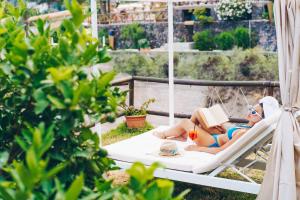 a woman laying in a hammock reading a book at Hotel Ferdinando Beach & Thermal Spa in Ischia