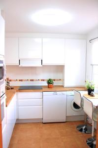 a white kitchen with white cabinets and a table at Niza Mar in Vélez-Málaga