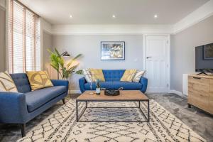 a living room with a blue couch and a coffee table at luxury 2 bed apartment, sea view, near the beach. in Llandrillo-yn-Rhôs
