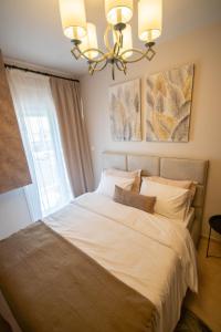 una camera da letto con un grande letto bianco e un lampadario a braccio di Kate's Luxury Apartment with Private Parking a Volos