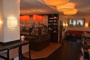 a restaurant with a bar with orange lights at Hotel Oyten am Markt in Oyten +11 photos