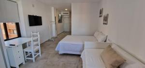 a small white room with two beds and a desk at Top Triana Sevilla in Seville