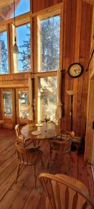 a dining room with a table and chairs and a clock at Ocean Views & Sunset Beach Cabin with soaker tub & fire pit in Powell River