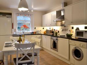 a kitchen with white cabinets and a table with a white table at Craigellie in Alyth