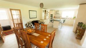 a kitchen and living room with a wooden table and chairs at The Byre in Strathyre