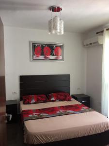 a bedroom with a bed with a black headboard and red pillows at apartment by the sea in Shëngjin