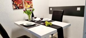 una mesa blanca con copas de vino y flores. en New Modern SelfCheckin PublicFreeParking HighSpeed Wifi KingSizeBed, en Baden-Baden