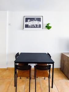 a black table with four chairs and a picture on the wall at Acogedor apartamento Besos de Elah in San Bartolomé