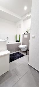 Baño blanco con bañera y lavamanos en New Modern SelfCheckin PublicFreeParking HighSpeed Wifi KingSizeBed en Baden-Baden