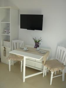 mesa blanca con 2 sillas y TV en la pared en Heidelandhaus Zühlke mit gemütlicher Südterrasse en Soltau