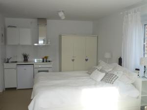 a white bedroom with a large bed and a kitchen at Heidelandhaus Zühlke mit gemütlicher Südterrasse in Soltau