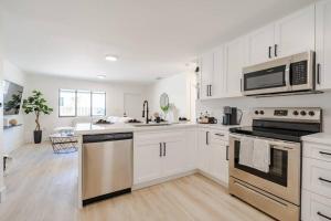 una cocina con armarios blancos y electrodomésticos de acero inoxidable en The Pass Through Brand New 2 - 1 Modern Villa, en Homestead