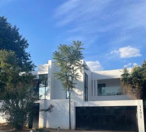 una casa bianca con un albero davanti di Stay In Carlazo - Unlimited WiFi, Solar backup a Roodepoort