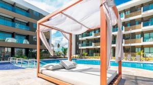 a bed in front of a building next to a swimming pool at Beautiful studio Muro Alto mana beach in Ipojuca