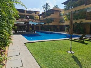 a swimming pool in front of a building with an umbrella at Relaxing ground floor 2 bed 2 bath appartment with pool walking distance from beach in Zihuatanejo