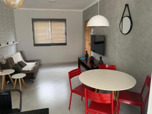 sala de estar con mesa blanca y sillas rojas en Apto 2o andar novo 2 dorm - próximo ao centro, en Poços de Caldas