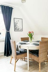 einen Esstisch mit Stühlen und eine Vase aus Blumen in der Unterkunft Modernes Apartment mit Balkon free Parking Netflix in Celle