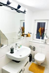 ein weißes Bad mit einem Waschbecken und einem WC in der Unterkunft Modernes Apartment mit Balkon free Parking Netflix in Celle